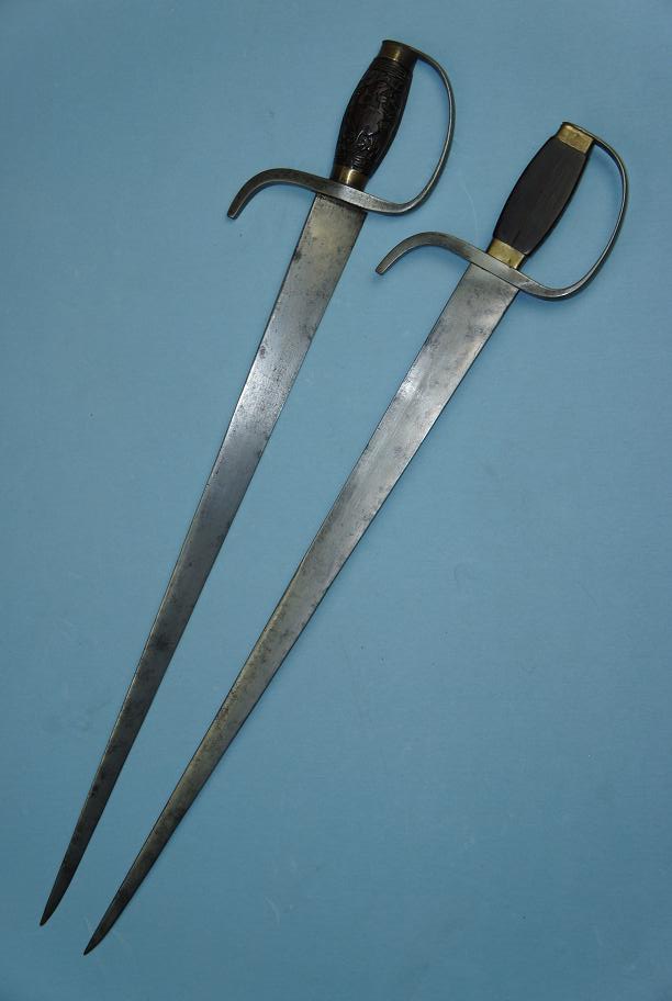 A set of mid. 19th century hudiedao. These swords are 63 cm long have strong blades with a thick triangular spine (14 mm at the forte). They were capable of cutting but clearly optimized for stabbing. The edge itself has a convex grind on one side, and a flat grind where it sits against the other sword when sheathed. The blades also feature steel D-guards and rosewood handles decorated with carved phoenixes. This images was provided courtesy of http://www.swordsantiqueweapons.com, a reliable source for authentic antique Chinese arms.
