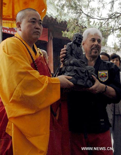 Shi Yongxin (L), current abbot of the Shaolin Temple, presents a sculpture of Bodhidharma to Professor Charles Mattera of United Studios of Self Defense (USSD) from the United States.